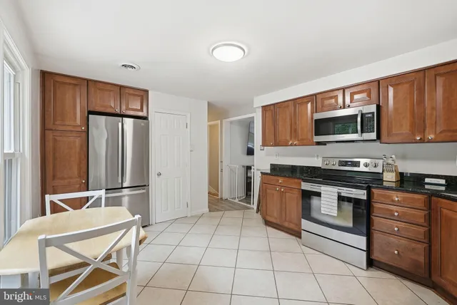 a kitchen with granite countertop a stove top oven microwave and cabinets