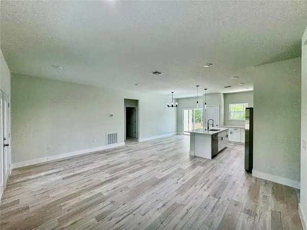 a kitchen with stainless steel appliances granite countertop a refrigerator a sink a stove and white cabinets with wooden floor