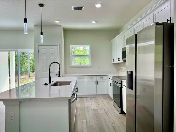 a kitchen with stainless steel appliances a sink a stove top oven a counter space and cabinets