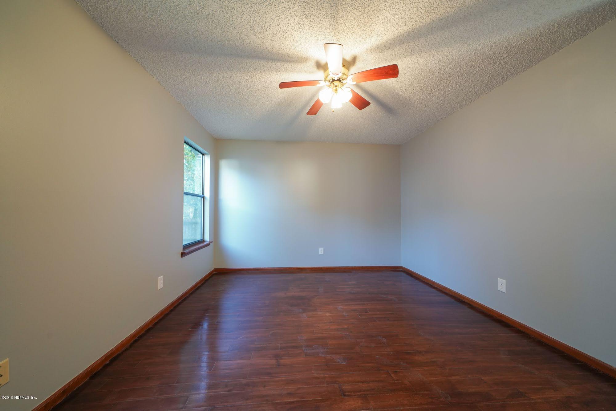 2148 Rothbury Drive Jacksonville, FL 32221 - Photo 16 of 36 an empty room with wooden floor fan and windows
