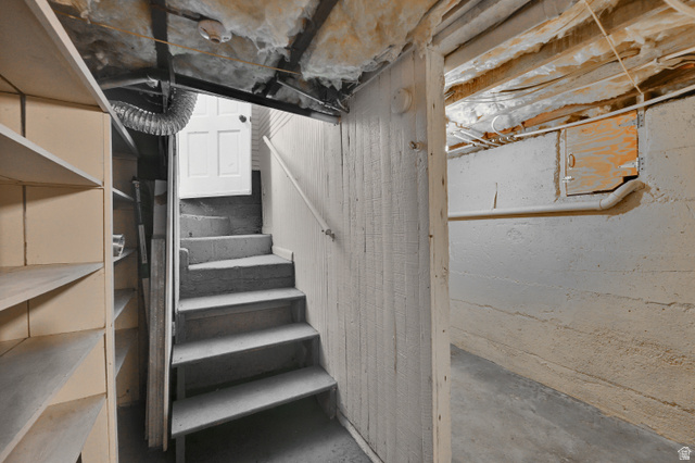 716 East Factory Street Garland, UT 84312 - Photo 24 of 30 Concrete basement with exposed joists, insulated ceiling, built-in shelving, and a painted wood staircase with a handrail