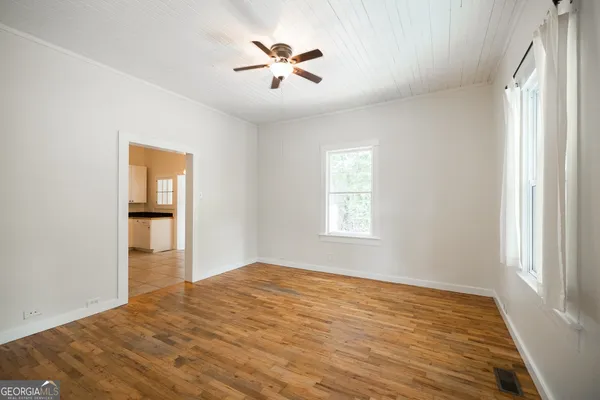a view of empty room with wooden floor and fan