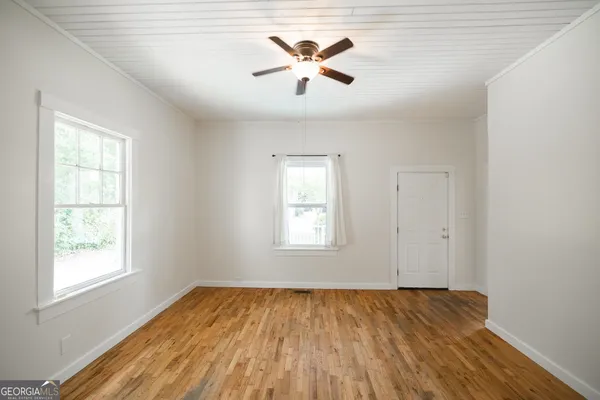 a view of empty room with wooden floor and fan