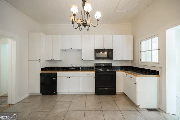 a kitchen with granite countertop white cabinets a stove top oven and dishwasher