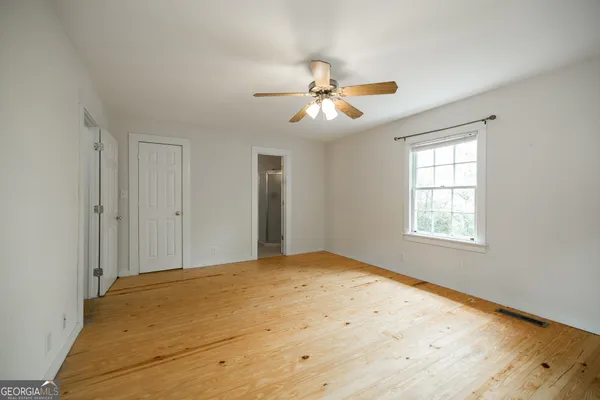 a view of empty room with wooden floor and fan