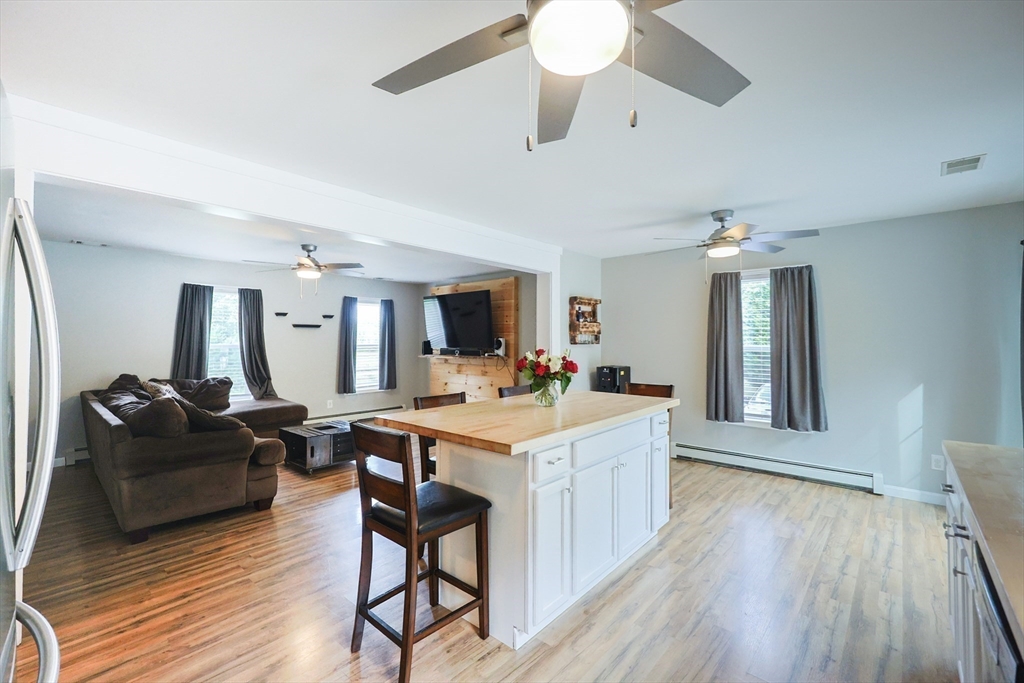 48 Wareham Street Carver, MA 02330 - Photo 23 of 42 a open kitchen with stainless steel appliances kitchen island granite countertop a stove a refrigerator a dining table and chairs with wooden floor