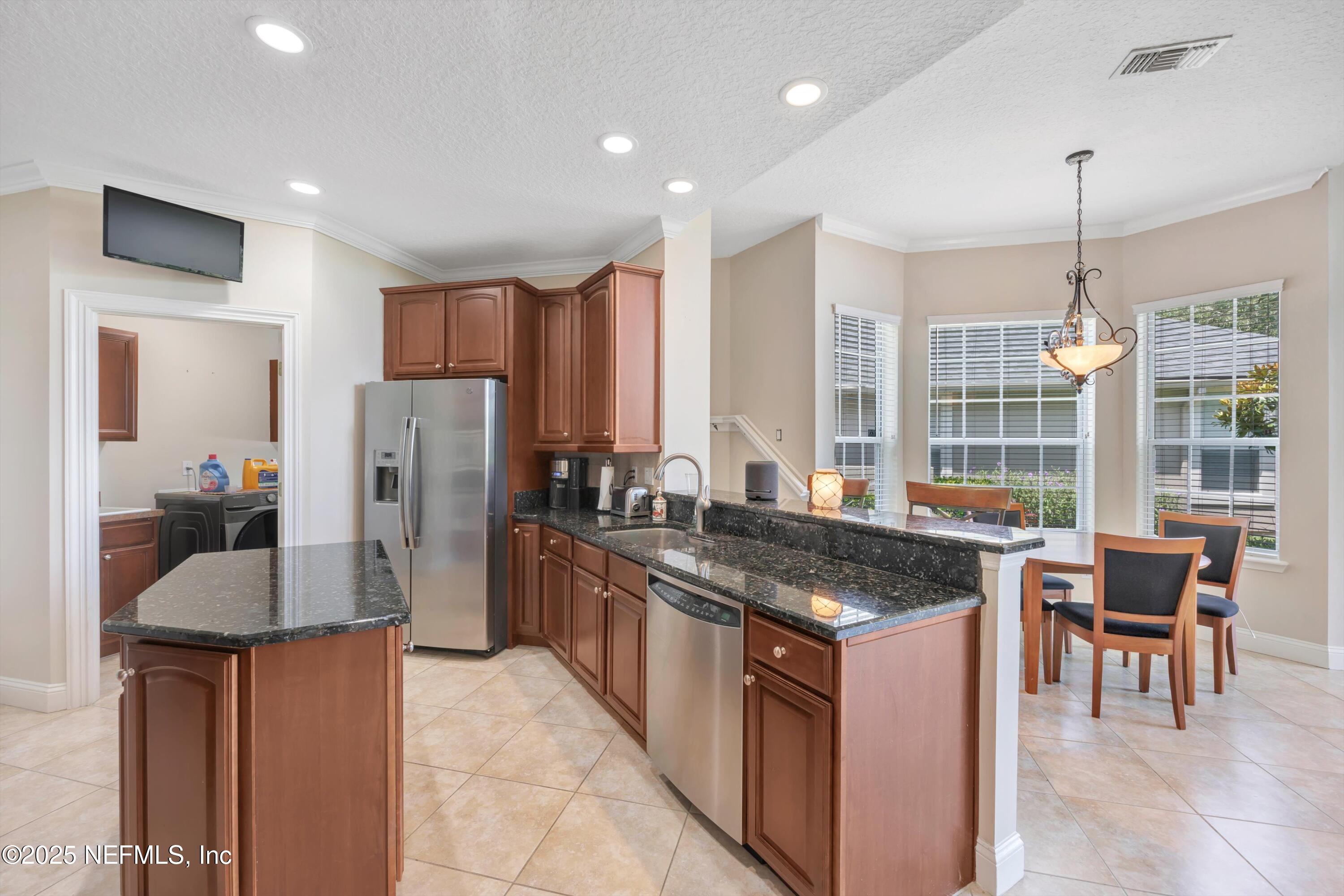 168 Pinehurst Pointe Drive St. Augustine, FL 32092 - Photo 21 of 72 a kitchen with stainless steel appliances granite countertop a stove a refrigerator a sink and a dining table with wooden floor