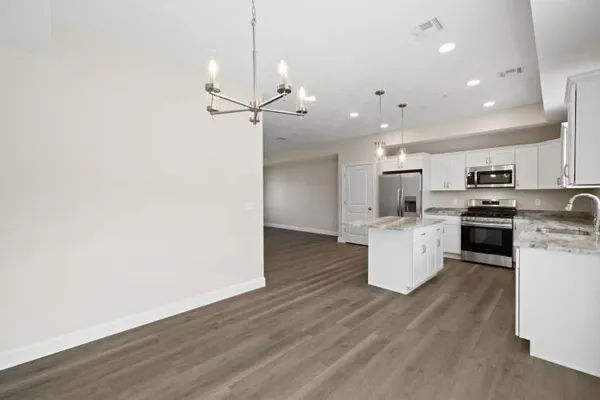 a large kitchen with stainless steel appliances a large counter top a sink a refrigerator and a window