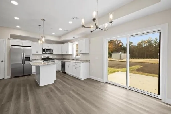 a kitchen with stainless steel appliances granite countertop a refrigerator a sink dishwasher a stove and white countertops with wooden floor