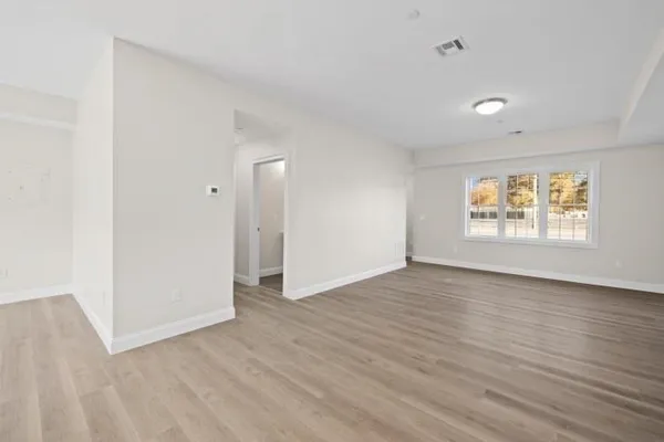 an empty room with wooden floor and windows