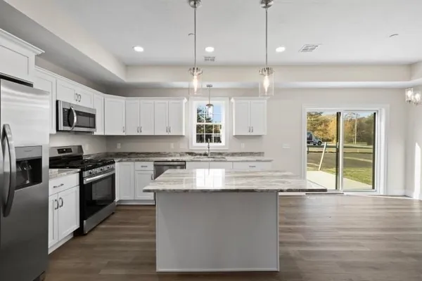 a large kitchen with granite countertop a stove top oven a sink a counter space and cabinets