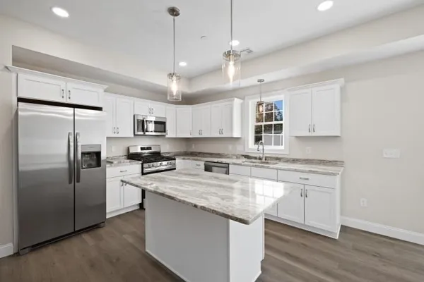 a kitchen with stainless steel appliances granite countertop a refrigerator a sink dishwasher a stove and white cabinets with wooden floor