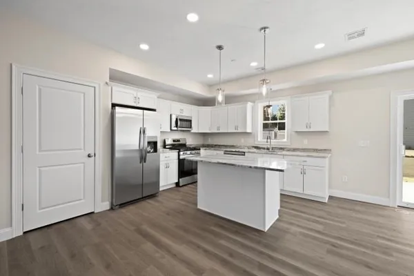 a kitchen with stainless steel appliances granite countertop a refrigerator a sink dishwasher a stove and white cabinets with wooden floor