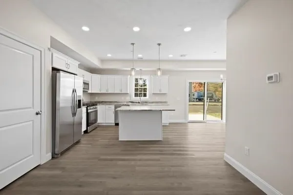 a kitchen with stainless steel appliances granite countertop a refrigerator a sink dishwasher and a stove with wooden floors