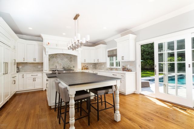 a kitchen with stainless steel appliances kitchen island wooden floors and white cabinets