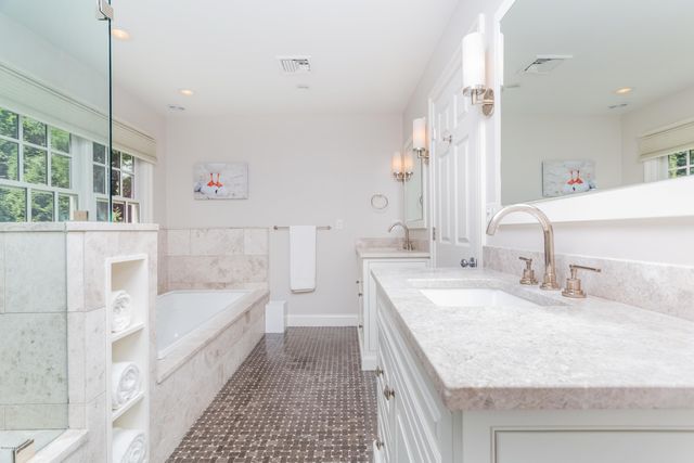 a bathroom with a granite countertop sink and a bathtub