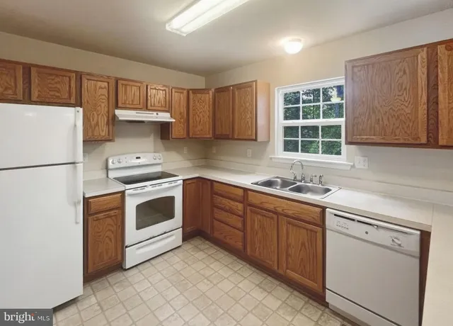 a kitchen with a white stove top oven sink and cabinets