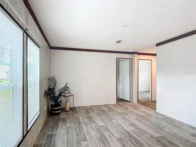 a view of empty room with wooden floor and fan