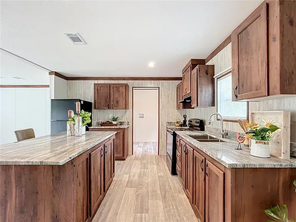 a kitchen with stainless steel appliances granite countertop a stove a sink dishwasher and a refrigerator with wooden cabinets