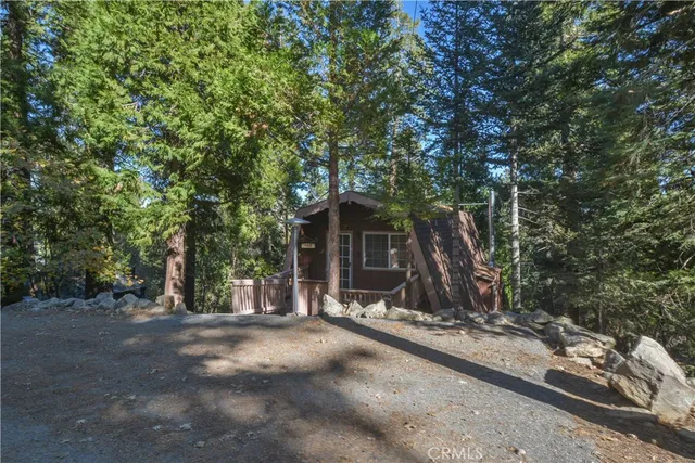 a view of a barn with large trees and wooden fence