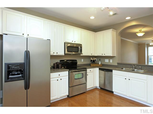 7833 Spungold Street Raleigh, NC 27617 - Photo 6 of 20 Kitchen is spacious and perfect for entertaining! Enjoy solid surface counters, black nickel hardware, hardwoods, double stainless sink, 42" cabinets with crown tops, recessed AND track lighting!