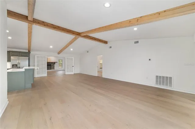 an empty room with windows and chandelier fan