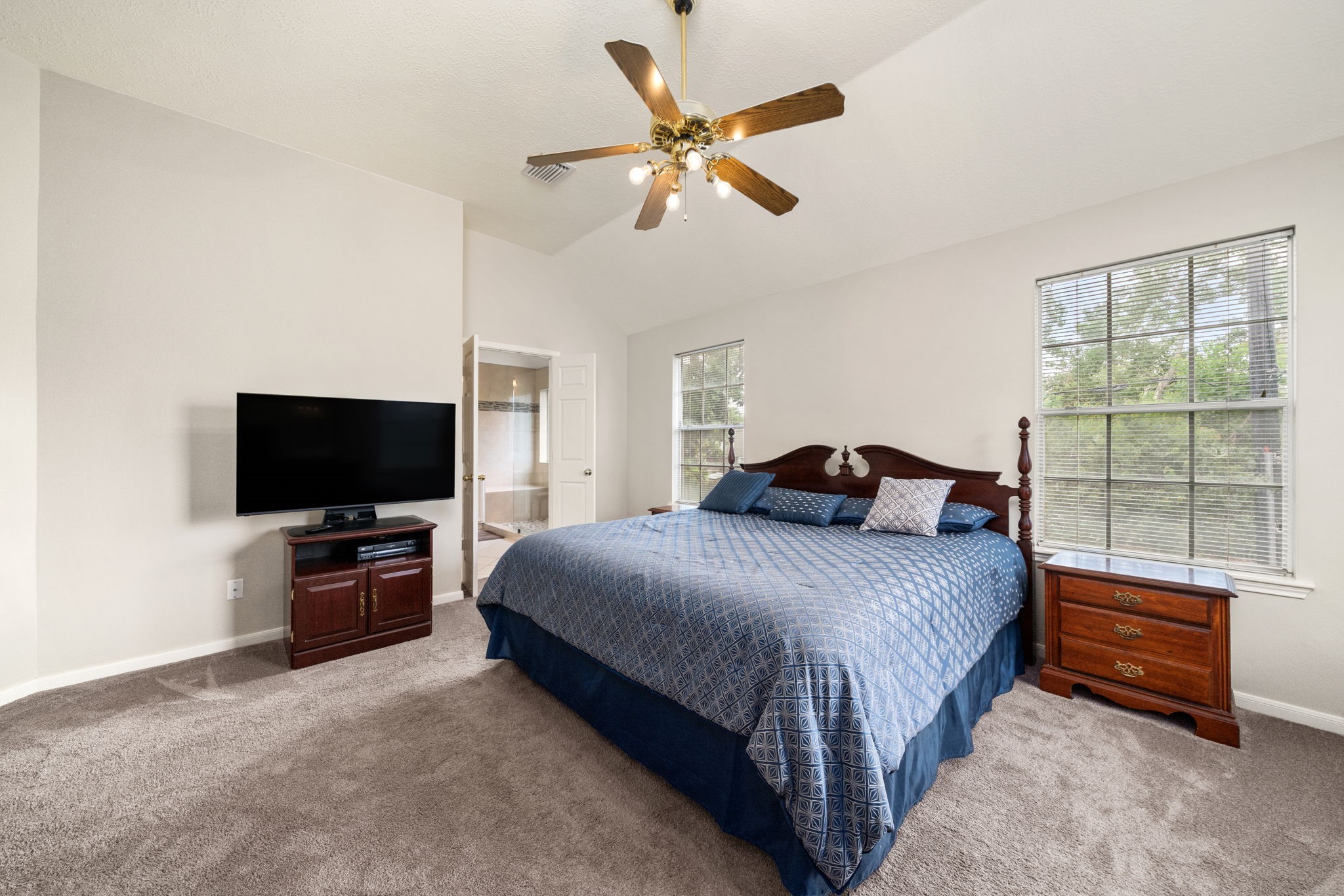9715 Therrell Drive Houston, TX 77064 - Photo 18 of 33 Generously sized primary bedroom with vaulted ceilings, ceiling fan, plush carpet, and natural light from dual windows with direct access to the en-suite bath.