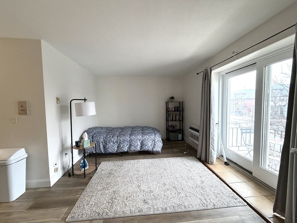 720 Bennington Street, Unit 207 Boston, MA 02128 - Photo 2 of 9 a bedroom with a bed and wooden floor