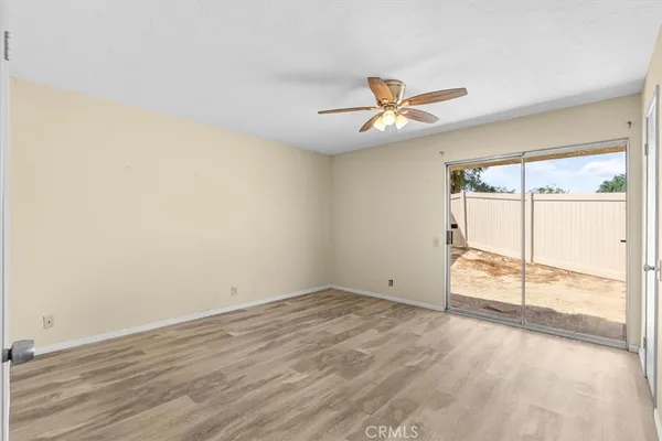 a view of empty room with wooden floor and ceiling fan