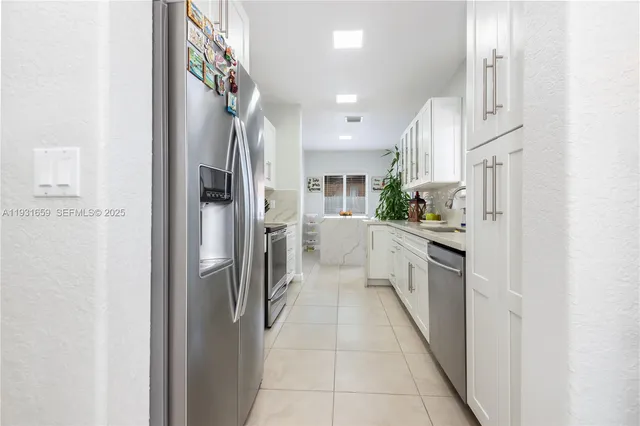 a kitchen with stainless steel appliances kitchen island granite countertop a refrigerator and a sink