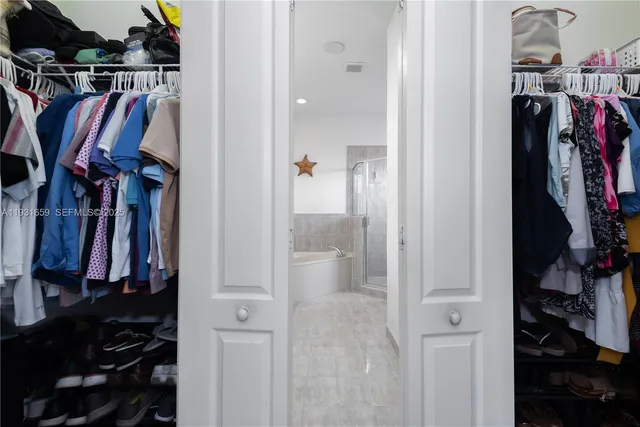 a view of walk in closet with clothes and shoes