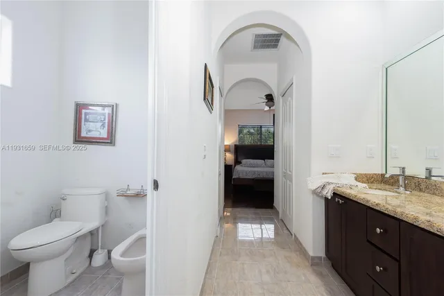 a spacious bathroom with a granite countertop toilet a sink and a mirror