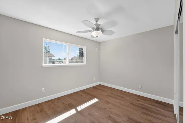 a view of an empty room with a window and wooden floor