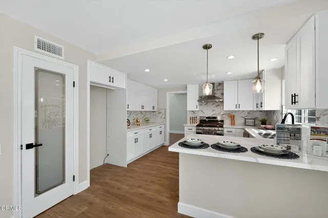a kitchen with stainless steel appliances a sink stove and wooden floor