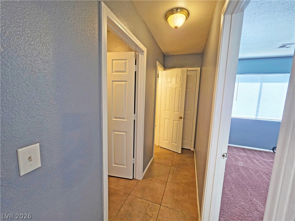 1444 Star Road, Unit 3 Pahrump, NV 89048 - Photo 13 of 35 A well-lit corridor connects various rooms, showcasing diverse flooring options.
