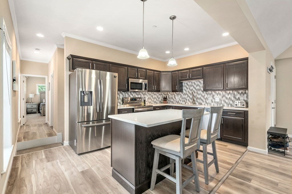 1 Elm Street, Unit 4 Boston, MA 02122 - Photo 7 of 15 a kitchen with stainless steel appliances a refrigerator sink and wooden cabinets
