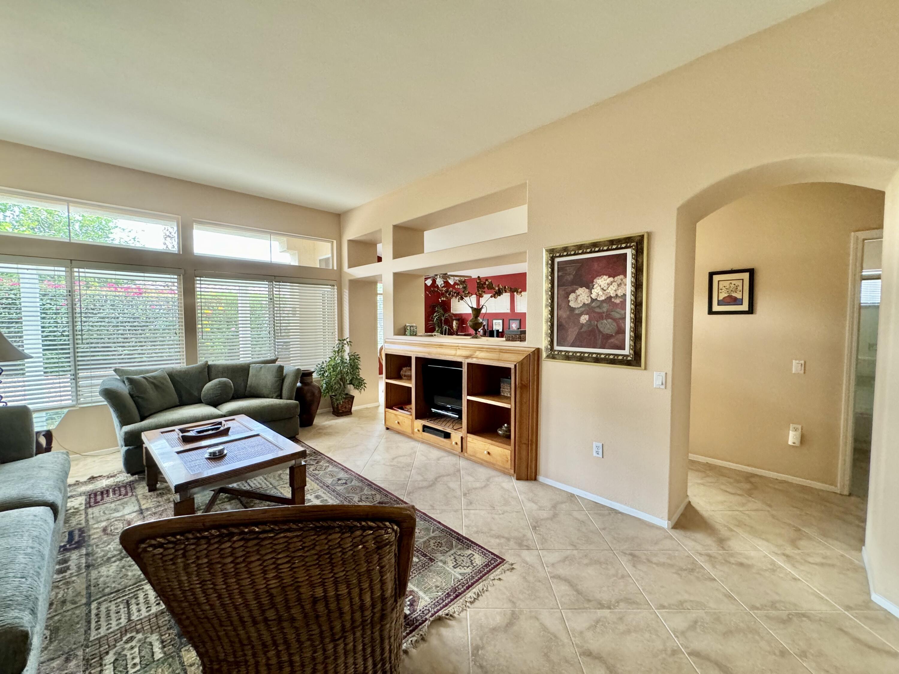 78376 Moongold Road Palm Desert, CA 92211 - Photo 1 of 36 a living room with furniture a flat screen tv and a floor to ceiling window
