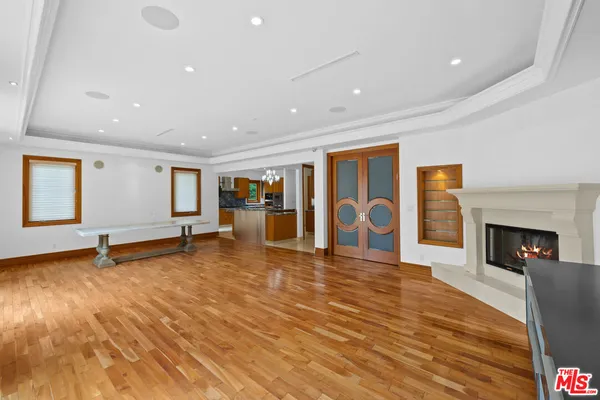 a view of an empty room with wooden floor and a fireplace