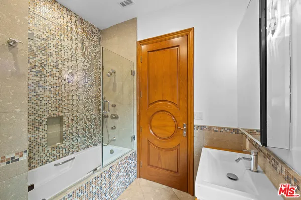 a bathroom with a bathtub shower sink vanity and mirror