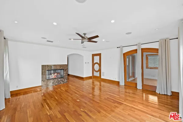 a view of an empty room with window and wooden floor