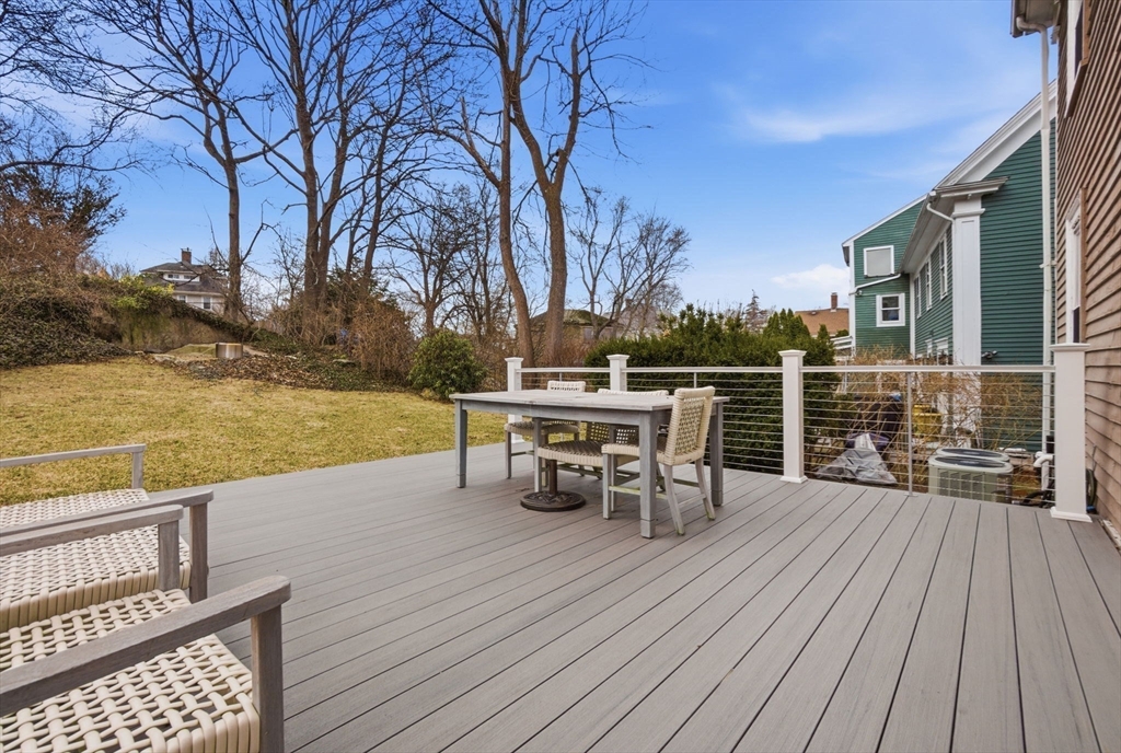 5 Pickett Street Beverly, MA 01915 - Photo 17 of 30 a view of a roof deck with table and chairs a barbeque with wooden floor and fence