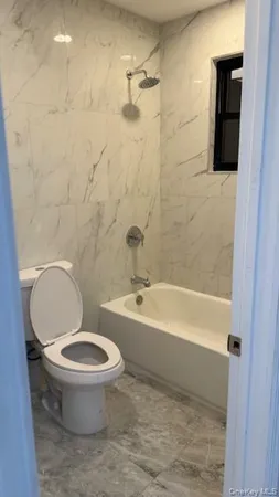 a white toilet sitting next to a bath tub and a shower