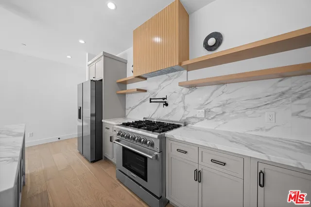 a large kitchen with stainless steel appliances granite countertop a sink a stove and a refrigerator