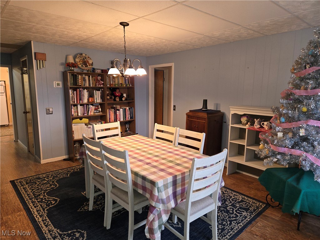 1962 Zenobia Road Norwalk, OH 44857 - Photo 10 of 30 Dining area featuring wood walls, dark wood-type flooring, and an inviting chandelier