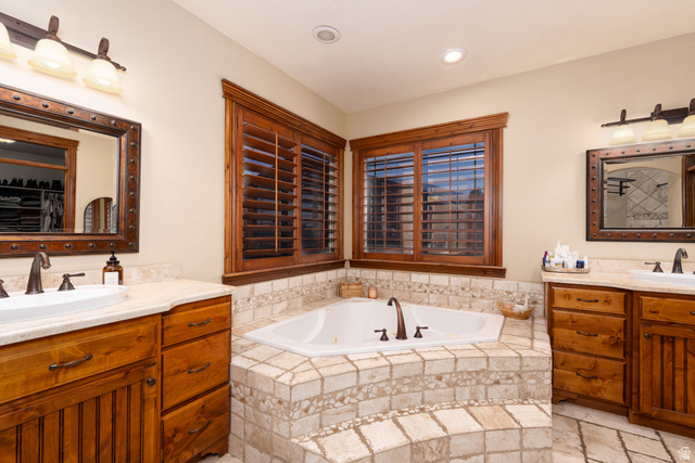 687 South 2080th Street East Springville, UT 84663 - Photo 17 of 149 Built-in corner tub with tiled surround, wood-finish plantation shutters, dual vanities with integrated sinks, and individual sconce lighting fixtures