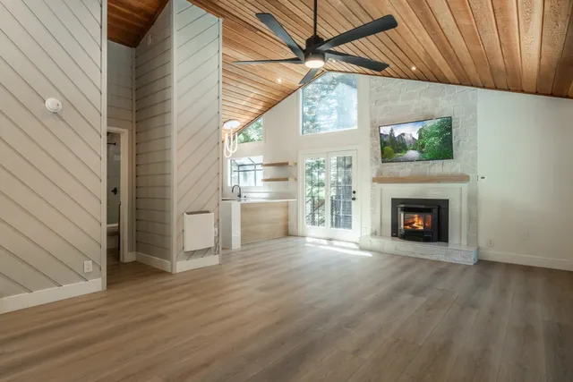 a view of an empty room with wooden floor fireplace and a window