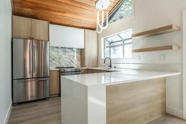 a kitchen with stainless steel appliances granite countertop a refrigerator a sink and a stove