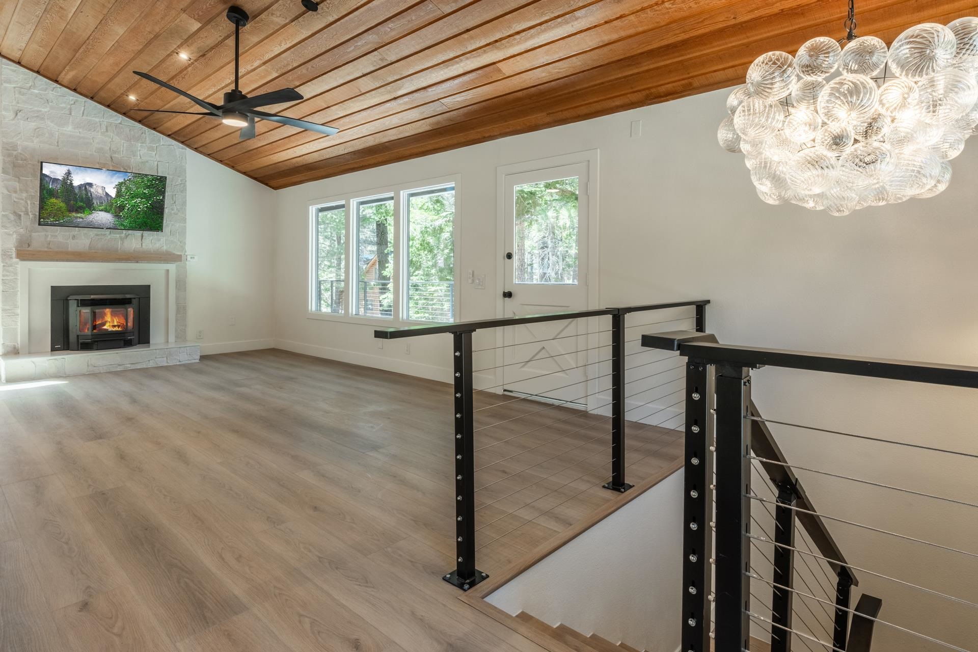 235 Forest Trail Mammoth Lakes, CA 93546 - Photo 6 of 35 Unfurnished living room featuring wooden ceiling, vaulted ceiling, light wood-style floors, a chandelier, and a glass covered fireplace