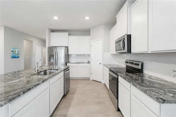 a large kitchen with stainless steel appliances granite countertop a sink stove and cabinets