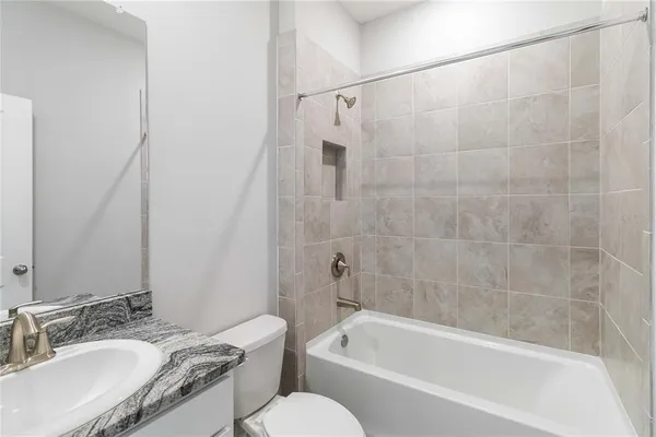 a bathroom with a granite countertop bathtub shower sink vanity and toilet